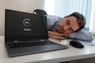 A new operating system update. software is in process of updating. The employee is tired and sleeps on the desktop. long wait