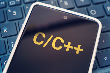 C Programming language for mobile development, concept. Smartphone on the laptop keyboard, the programmer workplace. inscription on mobile phone screen ,