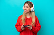 © luismolinero - Young Uruguayan woman playing with a video game controller isolated on blue looking side