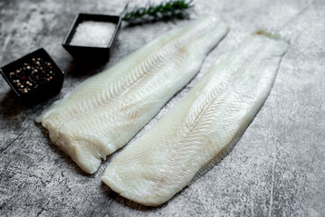 Fresh raw fillet of white fish Pangasius with spices on a stone background