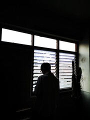 Turn back, Asian young man stands near window in the old building and looking at screen, reading message on his mobile phone, Take a break from work.