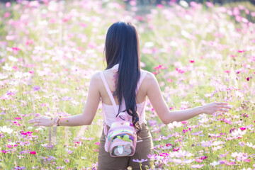 Wall Mural - Beautiful woman happy traveler walking in the flowers garden. Young woman smile and relaxing with happy  around outdoor garden. Woman's hand touching and enjoying beauty cosmos flowers.Travel concept.
