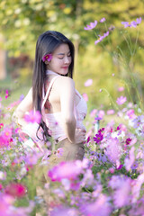 Wall Mural - Beautiful woman happy traveler walking in the flowers garden. Young woman smile and relaxing with happy  around outdoor garden. Woman's hand touching and enjoying beauty cosmos flowers.Travel concept.