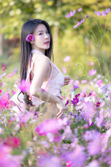 Wall Mural - Beautiful woman happy traveler walking in the flowers garden. Young woman smile and relaxing with happy  around outdoor garden. Woman's hand touching and enjoying beauty cosmos flowers.Travel concept.