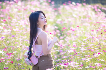 Wall Mural - Beautiful woman happy traveler walking in the flowers garden. Young woman smile and relaxing with happy  around outdoor garden. Woman's hand touching and enjoying beauty cosmos flowers.Travel concept.