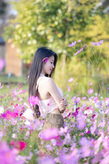 Wall Mural - Beautiful woman happy traveler walking in the flowers garden. Young woman smile and relaxing with happy  around outdoor garden. Woman's hand touching and enjoying beauty cosmos flowers.Travel concept.