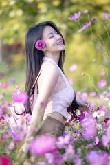 Wall Mural - Beautiful woman happy traveler walking in the flowers garden. Young woman smile and relaxing with happy  around outdoor garden. Woman's hand touching and enjoying beauty cosmos flowers.Travel concept.