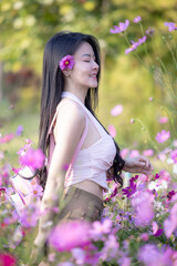 Wall Mural - Beautiful woman happy traveler walking in the flowers garden. Young woman smile and relaxing with happy  around outdoor garden. Woman's hand touching and enjoying beauty cosmos flowers.Travel concept.