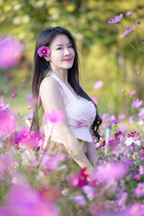 Wall Mural - Beautiful woman happy traveler walking in the flowers garden. Young woman smile and relaxing with happy  around outdoor garden. Woman's hand touching and enjoying beauty cosmos flowers.Travel concept.