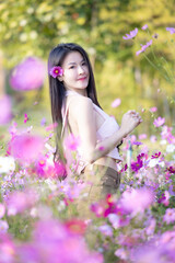 Wall Mural - Beautiful woman happy traveler walking in the flowers garden. Young woman smile and relaxing with happy  around outdoor garden. Woman's hand touching and enjoying beauty cosmos flowers.Travel concept.