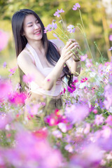 Wall Mural - Beautiful woman happy traveler walking in the flowers garden. Young woman smile and relaxing with happy  around outdoor garden. Woman's hand touching and enjoying beauty cosmos flowers.Travel concept.