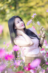 Wall Mural - Beautiful woman happy traveler walking in the flowers garden. Young woman smile and relaxing with happy  around outdoor garden. Woman's hand touching and enjoying beauty cosmos flowers.Travel concept.