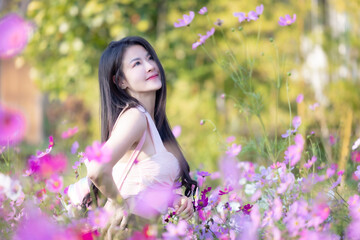 Wall Mural - Beautiful woman happy traveler walking in the flowers garden. Young woman smile and relaxing with happy  around outdoor garden. Woman's hand touching and enjoying beauty cosmos flowers.Travel concept.