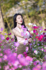 Wall Mural - Beautiful woman happy traveler walking in the flowers garden. Young woman smile and relaxing with happy  around outdoor garden. Woman's hand touching and enjoying beauty cosmos flowers.Travel concept.