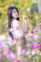 Wall Mural - Beautiful woman happy traveler walking in the flowers garden. Young woman smile and relaxing with happy  around outdoor garden. Woman's hand touching and enjoying beauty cosmos flowers.Travel concept.