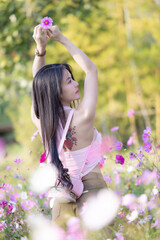 Wall Mural - Beautiful woman happy traveler walking in the flowers garden. Young woman smile and relaxing with happy  around outdoor garden. Woman's hand touching and enjoying beauty cosmos flowers.Travel concept.