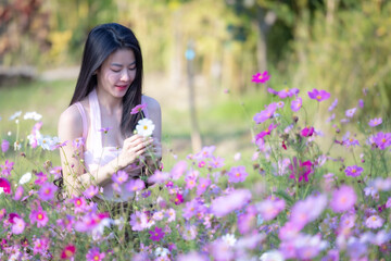 Wall Mural - Beautiful woman happy traveler walking in the flowers garden. Young woman smile and relaxing with happy  around outdoor garden. Woman's hand touching and enjoying beauty cosmos flowers.Travel concept.