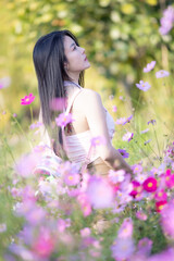 Wall Mural - Beautiful woman happy traveler walking in the flowers garden. Young woman smile and relaxing with happy  around outdoor garden. Woman's hand touching and enjoying beauty cosmos flowers.Travel concept.
