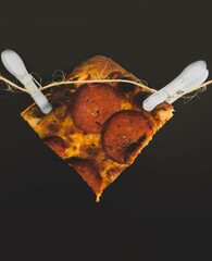 Wall Mural - Slice of pepperoni pizza held up with clothespins against a black background