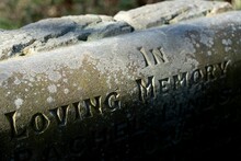 A Christian Gravestone Reads, "In Loving Memory" With The Name Obscured In Shadow. Concept Of Death