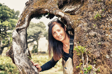 Wall Mural - Portrait of woman framed inside the roots of a tree trunk