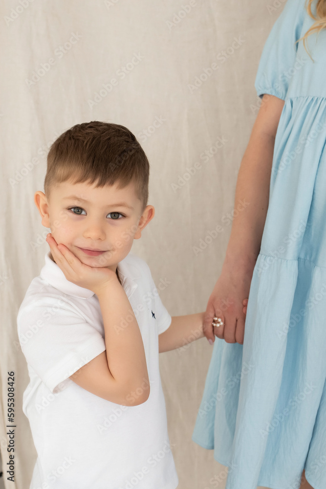 cute little boy stands next to pregnant mom's belly. mom and son hold