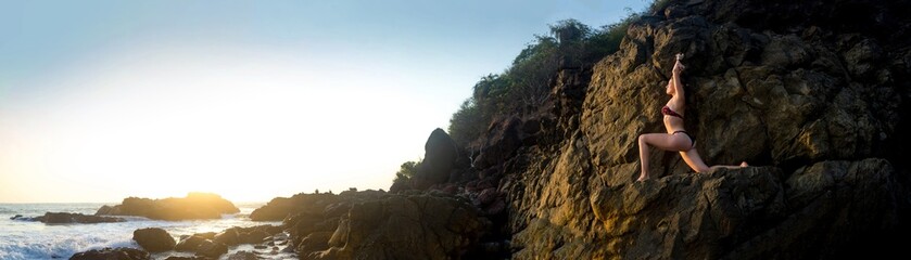 Young beautiful healthy woman making meditation on the rocks, sunset on the sea. Arambol, Goa, India.