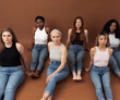 © Artem Varnitsin - Six different females on a brown background. Group of six women with different body types and skin tones are looking at camera. Females of different ages in casuals sitting together in studio.