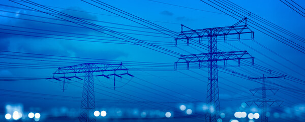 high-voltage tower and power lines with abstract defocused city lights at night, transmission of ele
