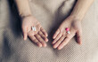 Female hands hold and offer two choice medicine pills capsule for chosen. White and pink candy or meds compare to choose from. Concept decision making or indecisiveness.