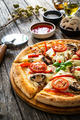 Wall Mural - Circle vegetarian pizza with mozzarella cheese, mushrooms and tomatoes on wooden table
