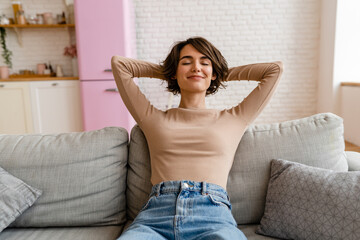 Wall Mural - pretty young woman realxing at home sitting on sofa, smiling, happy, free time