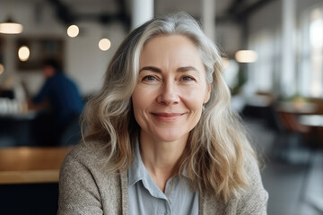 Portrait of a senior confident female entrepreneur sitting at her working desk and posing smiling at camera in her white office. Generative AI