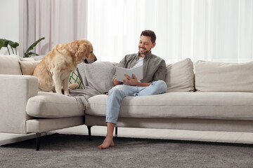 Poster - Man reading book on sofa near his cute Labrador Retriever at home