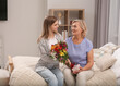 © New Africa - Young daughter congratulating her mom with flowers at home. Happy Mother's Day