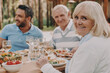 © gstockstudio - Happy multi-generation family enjoying dinner while sitting outdoors together