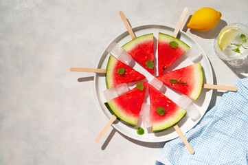 Wall Mural - Fresh slices of watermelon popsicles in a plate with ice cubes. Summer abstract food.