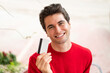 © luismolinero - Young handsome man holding a credit card with happy expression