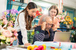 © anon - Elder senior man florist talking on smartphone using laptop at florist.portrait of mature male small business owner using laptop and looking at camera in flower shop