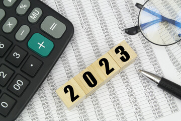 Wall Mural - Eyeglasses, pen, calculator and wooden cubes with numbers 2023. Business in 2023 concept.