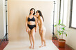 Two young latin women smiling in their underwear talking about self love