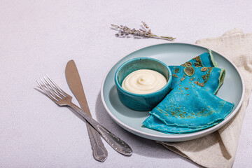 Wall Mural - Thin blue pancakes with creamy sauce. Healthy vegan non lactose, gluten free food, breakfast concept