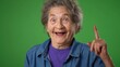 © Robert Peak - Extreme closeup of funny thinking thoughtful elderly old toothless woman with great idea points with finger on green screen background.