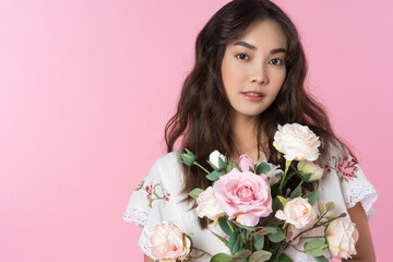 Canvas Print - Young Asian woman holding a rose bouquet on hand isolated pink color background