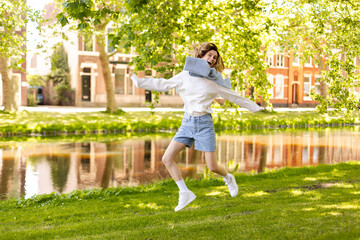 Sticker - Portrait of beautiful woman smiling and jumping in park at sunny day. Outdoor portrait of a smiling curly blonde girl. Happy cheerful girl laughing at park wear sweater, white long sleeves, shorts