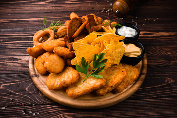 Wall Mural - Dinner fried chicken fillet, crispy onion rings, cheese sticks, garlic croutons, nachos, sauces and greens.