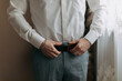 © Vasil - Details. A man in a white shirt and gray pants adjusts his stylish belt. Masculine style. Fashion. Business