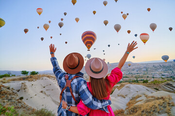 traveling couple with open arms standing together in scenic valley in anatolia, kapadokya. flying ho