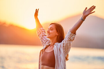 portrait of calm happy smiling free woman with open arms and closed eyes enjoys a beautiful moment l