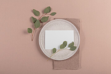 Wall Mural - Blank white invitation stationery card on plate with eucalyptus leaves